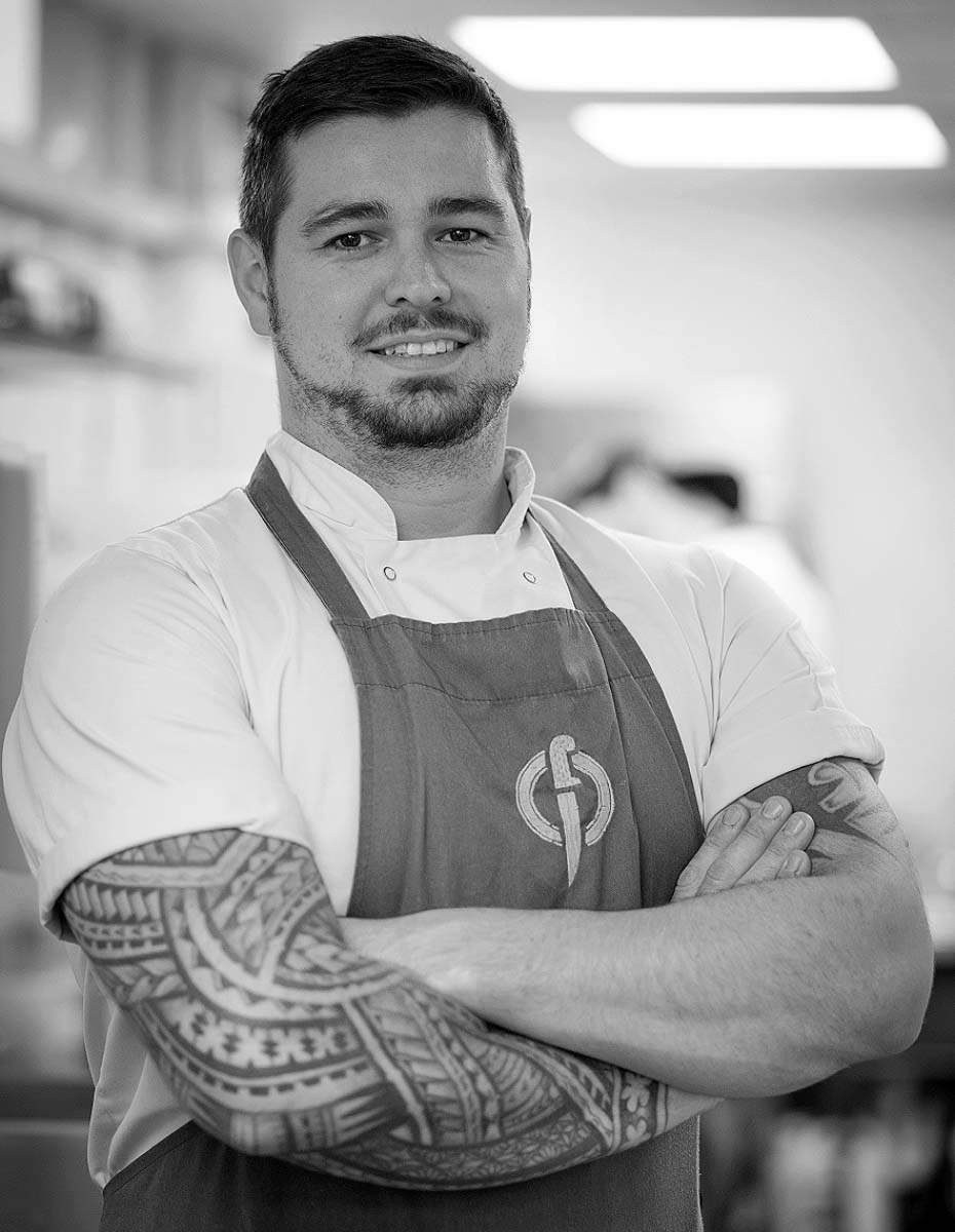 Fletcher Andrews, head chef and owner of Fletcher's Restaurant, Plymouth, dressed in chef's whites and standing proudly in his kitchen.