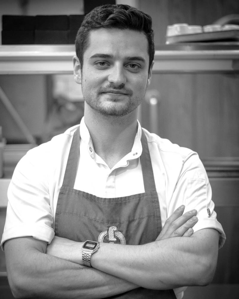 Meet Jack, a talented chef at Fletcher's Restaurant, standing proudly in the kitchen where he creates delicious dishes for our guests.