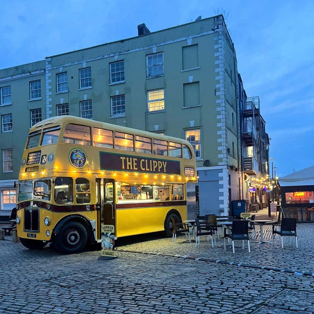 The Clippy parked on Plymouth Barbican in the evening, beautifully lit up, offering a cozy and inviting atmosphere for visitors to enjoy delicious street food.