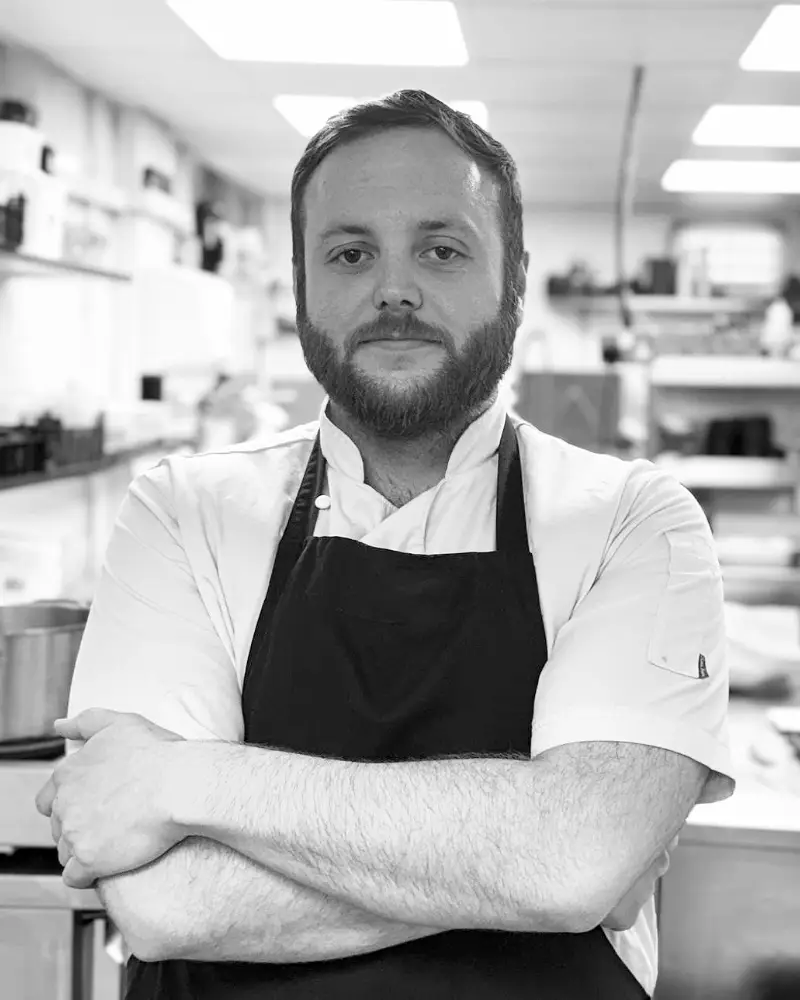 Meet Andy, one of our talented chefs at Fletcher's Restaurant, standing in the kitchen, where he crafts exceptional dishes for our guests.
