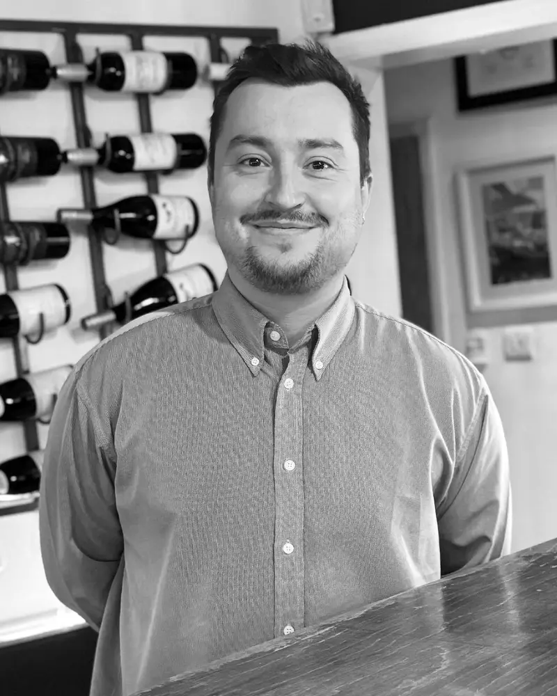 Meet Johmmy, the Assistant Manager at Fletcher's Restaurant, standing in the dining area, ready to ensure every guest has a fantastic dining experience.